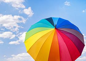 Parapluie de couleur arc-en-ciel contre ciel nuageux bleu