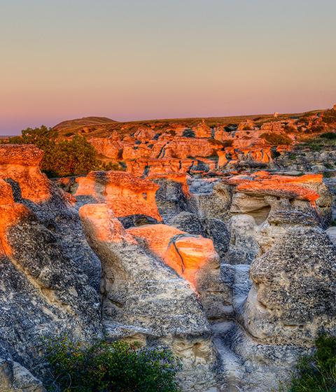 Sunrise shining over the Hoodoo badlands at Writing-on-Stone Provincial Park in Alberta, Canada.