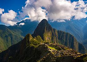 Machu Picchu illuminated by the warm light of the sunset. Wide angle view from the terraces above with picturesque sky and sun burst